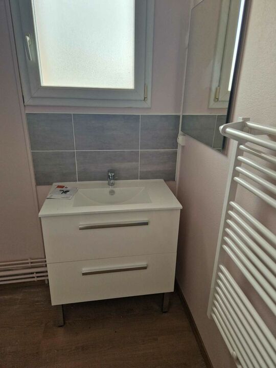 La salle de bain qui est équipée d'un meuble bas lavabo et d'un sèche serviette au mur